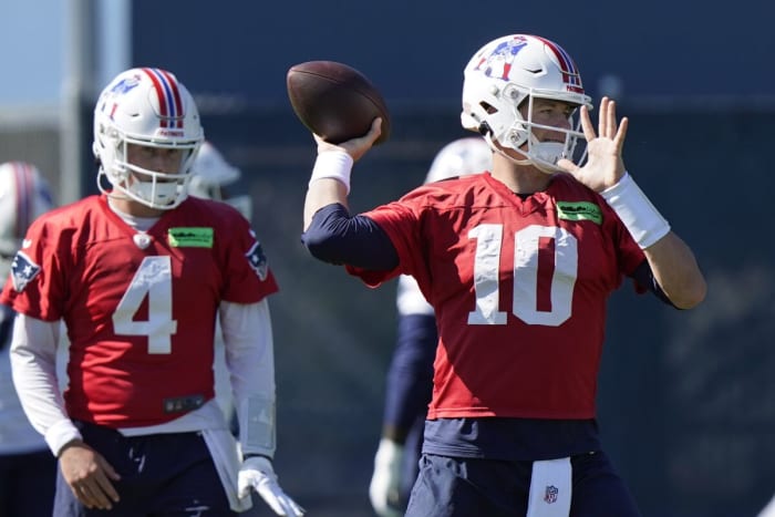 New England Patriots quarterback Mac Jones (10) winds up to pass as quarterback Bailey Zappe (4) looks on during an NFL football practice